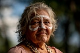 An Indigenous woman with white paint on her face