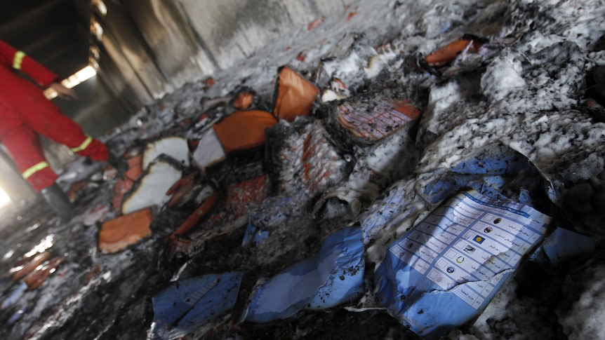 Burnt ballot papers lie on the floor of a warehouse that was used to store materials for Libya's upcoming elections.