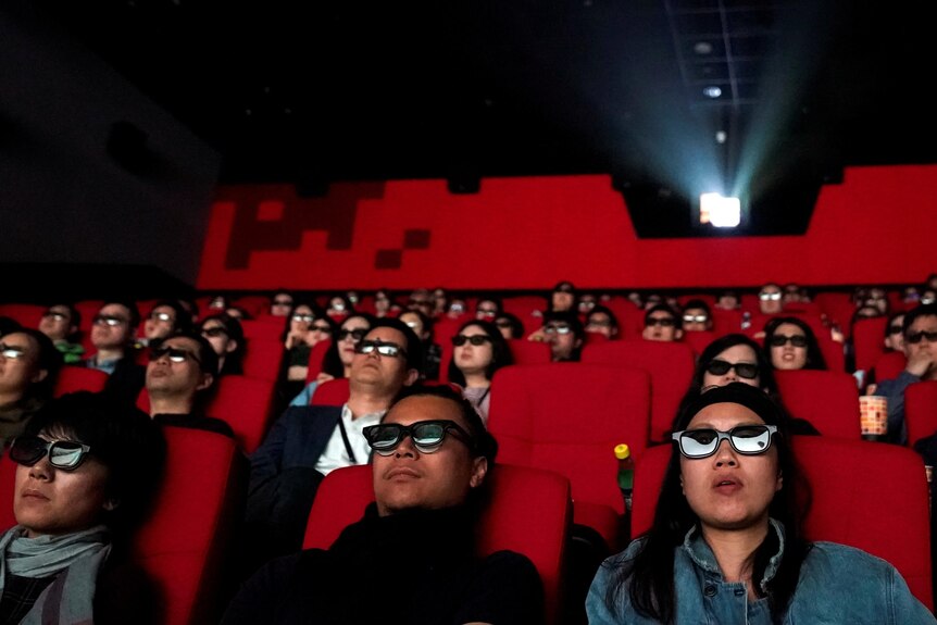 A cinema full of Chinese people watching a movie, wearing 3d glasses.