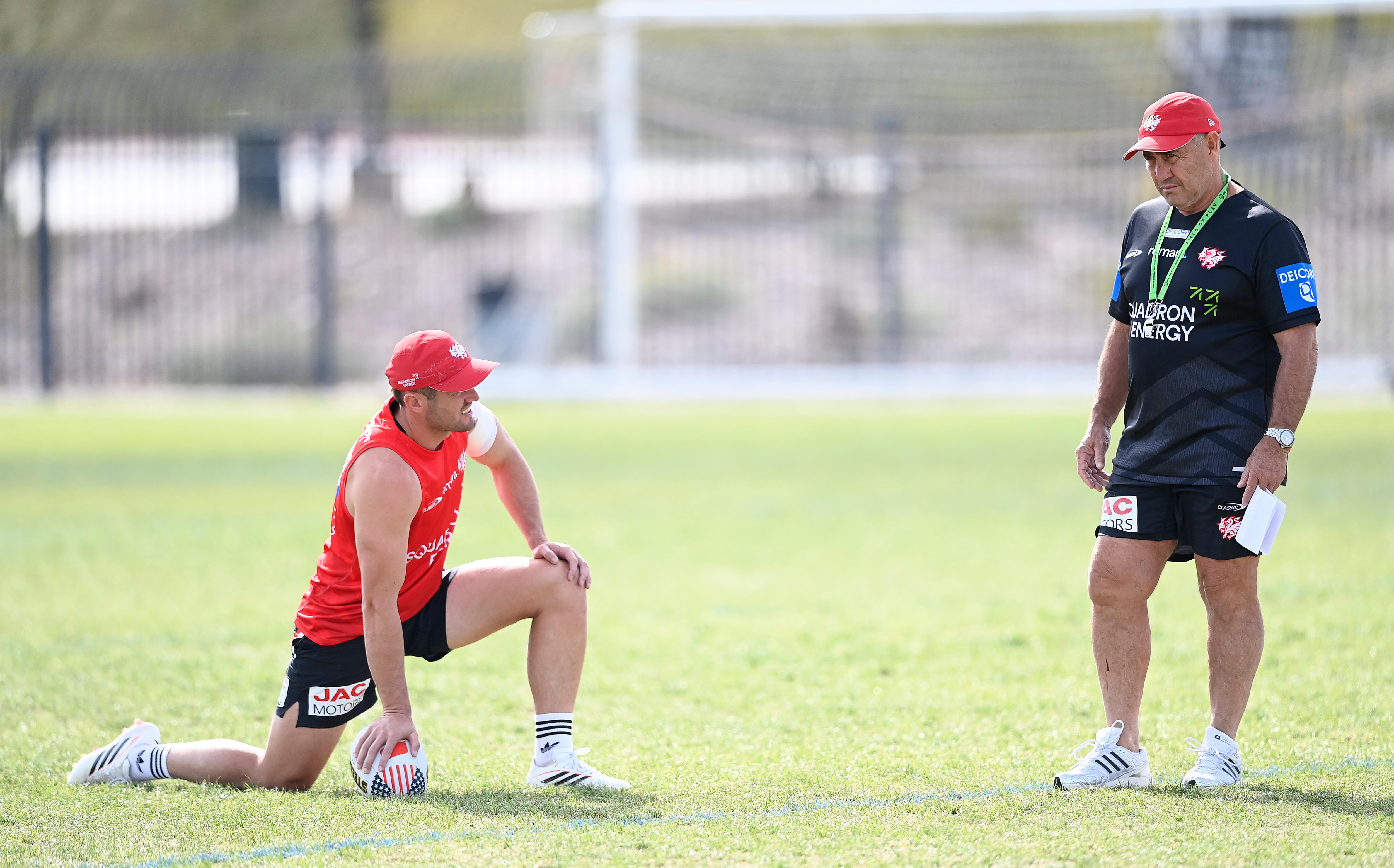 Dragons player Kyle Flanagan stretches as coach Shane Flanagan stands nearby at training.