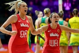 Two English netballers run in celebration while disappointed Australian players can be seen in the background