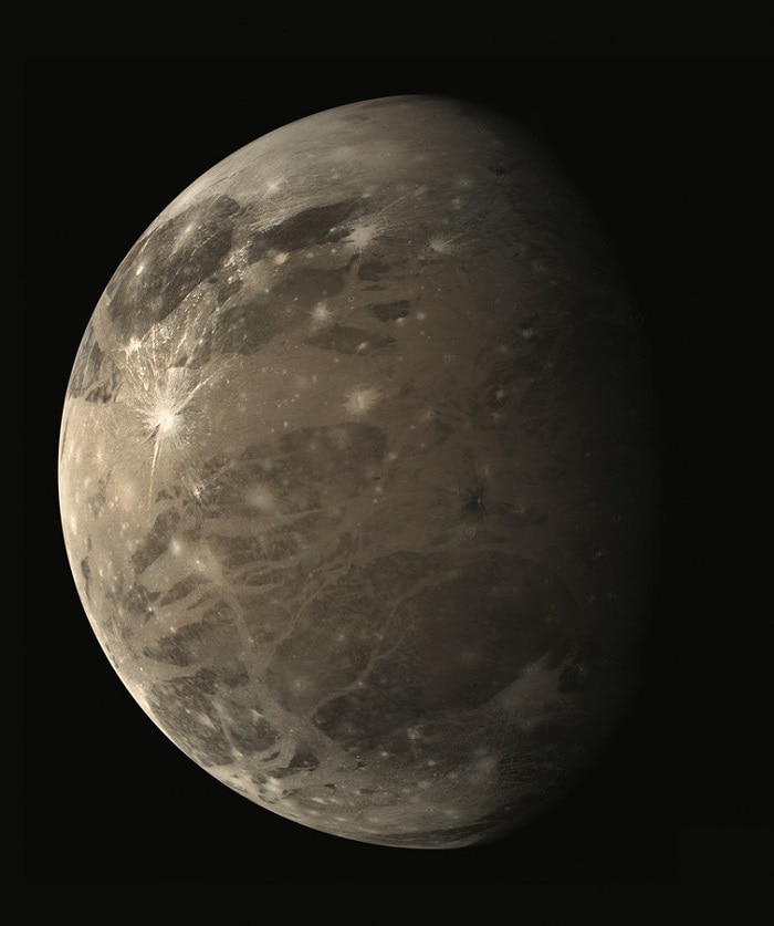 A view of Ganymede, grey-brown in colour and pocked with scars/craters