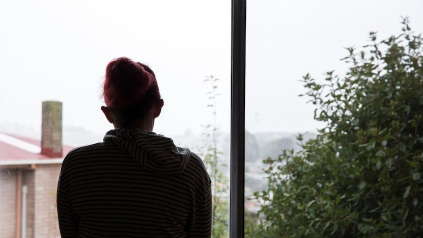 Women looks out of window on rainy day.