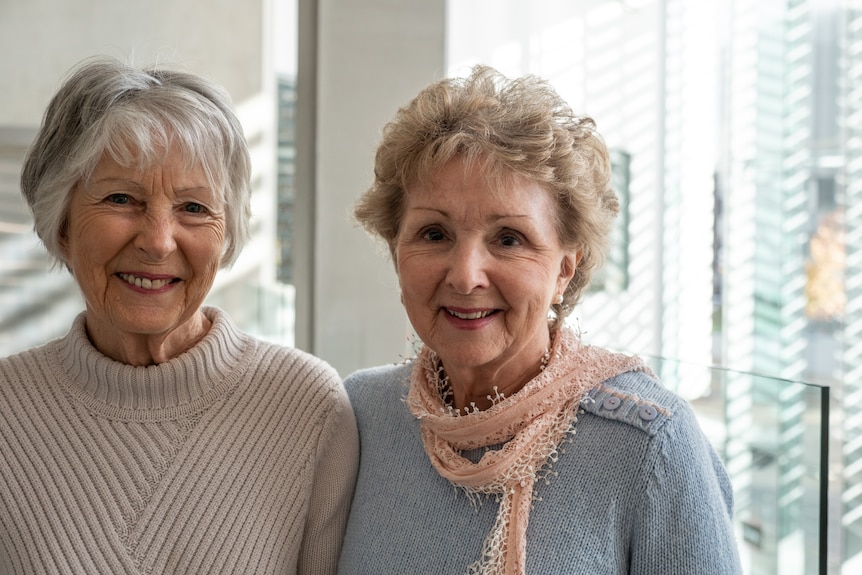 Two women in jumpers smiling at camera.
