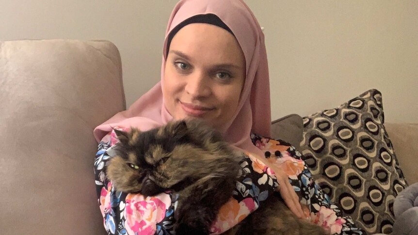 A woman in a headscarf with her cat.