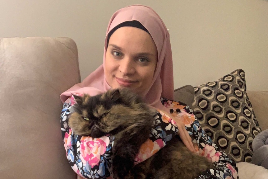 A woman in a headscarf with her cat.