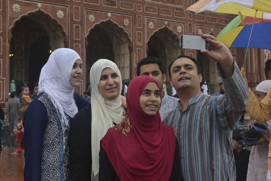 Pakistani devotees pose for photographs after offering Eid prayers