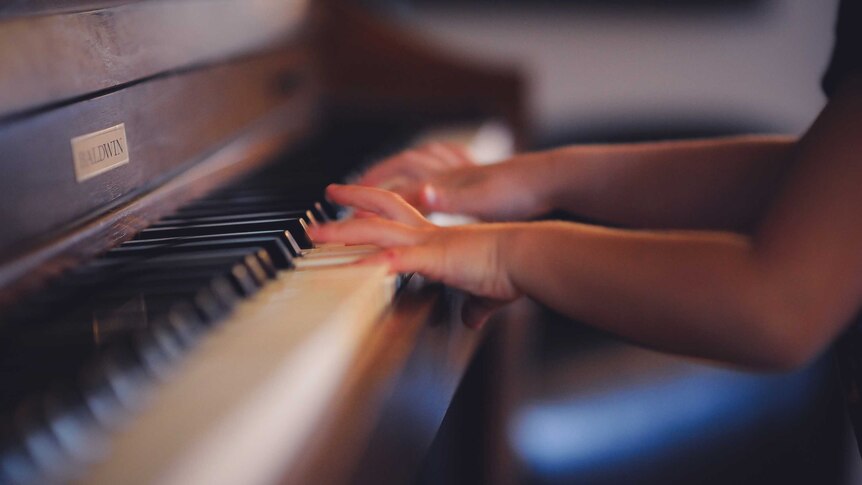 child hands at a piano