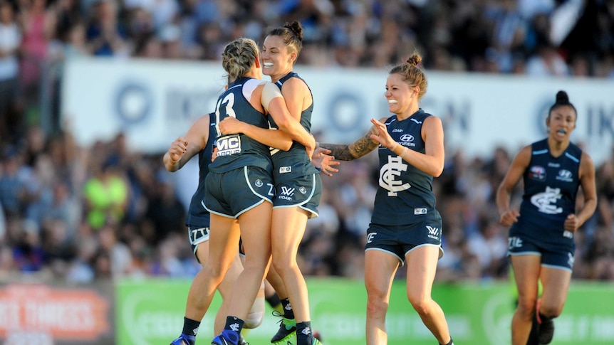 Lauren Arnell is mobbed by her Carlton teammates