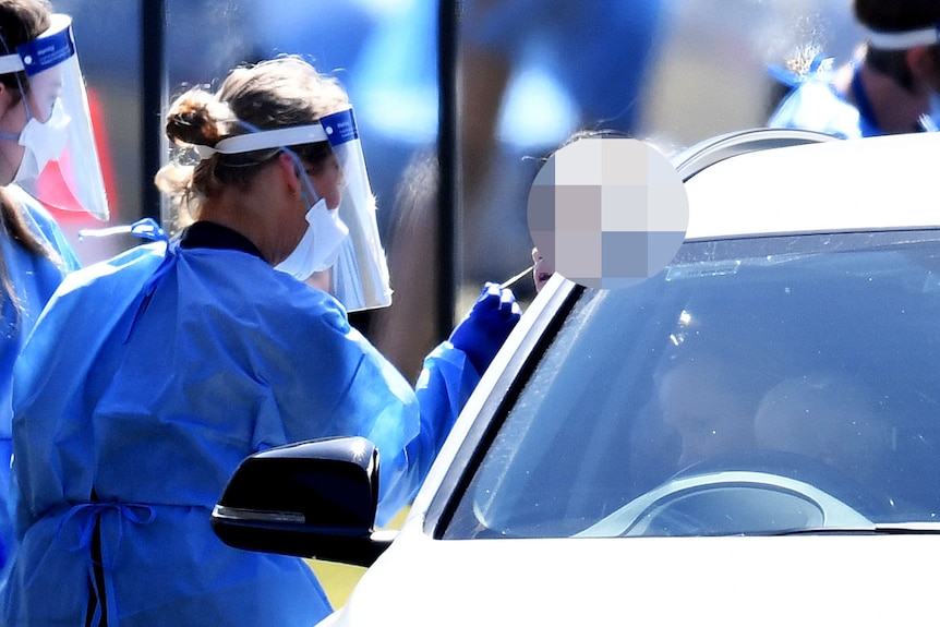 A health worker swabs a young girl in a car in the line-up at a pop-up COVID-19 testing station