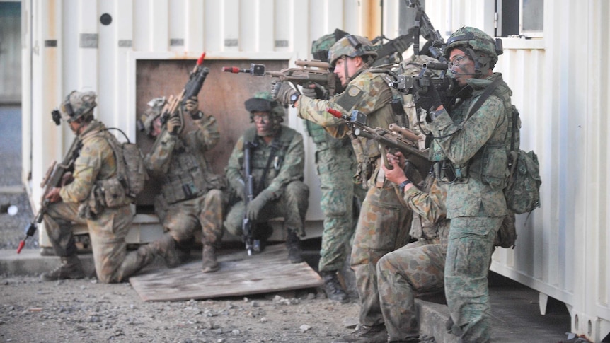 Australiand and Queensland troops hold weapons during a joint training exercise.