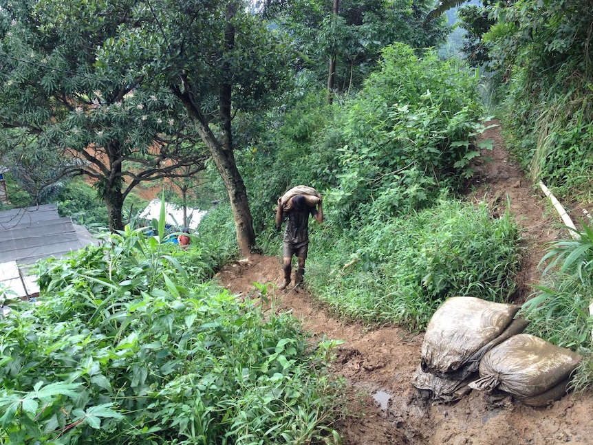 A worker in an illegal mine in West Java carts rocks.