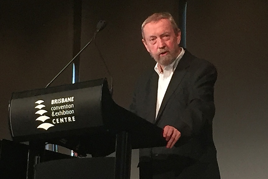 A man standing behind a lectern delivering a speech