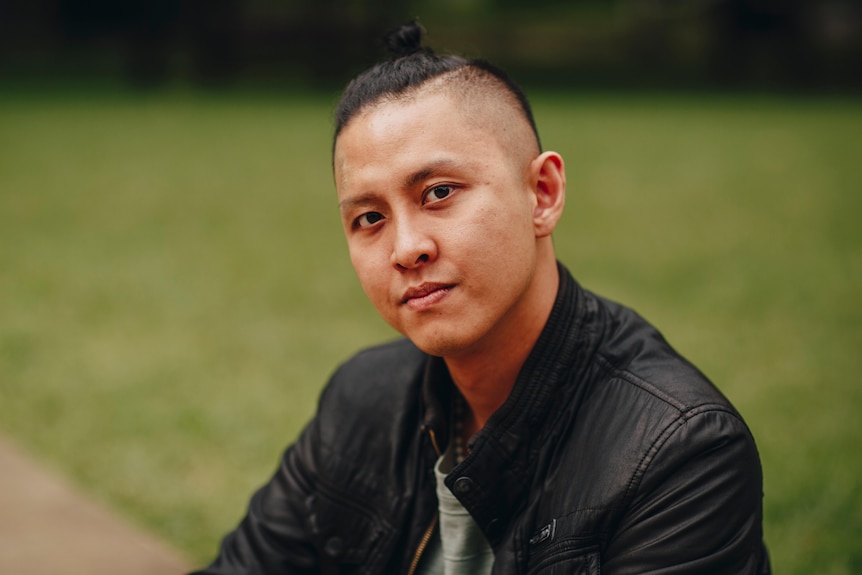 Mid-20s Vietnamese man Peter Nguyen looking at camera wearing man bun and leather jacket.