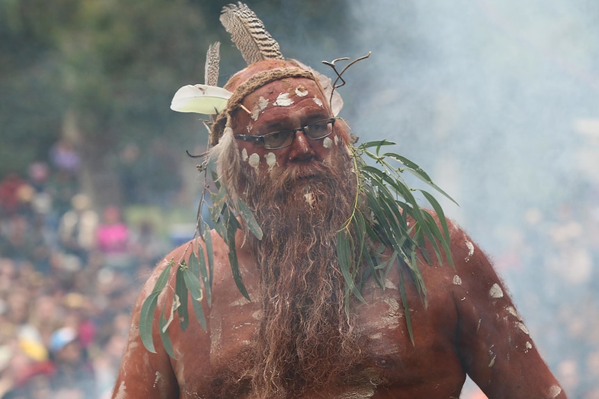 An Indigenous elder in traditional headdress and body paint performs a smoking ceremony at Golden Plains 2020