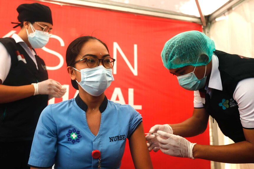 A nurse receives a shot of COVID-19 vaccine at a hospital in Bali