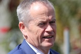 A tight head and shoulders shot of a smiling Bill Shorten outdoors.