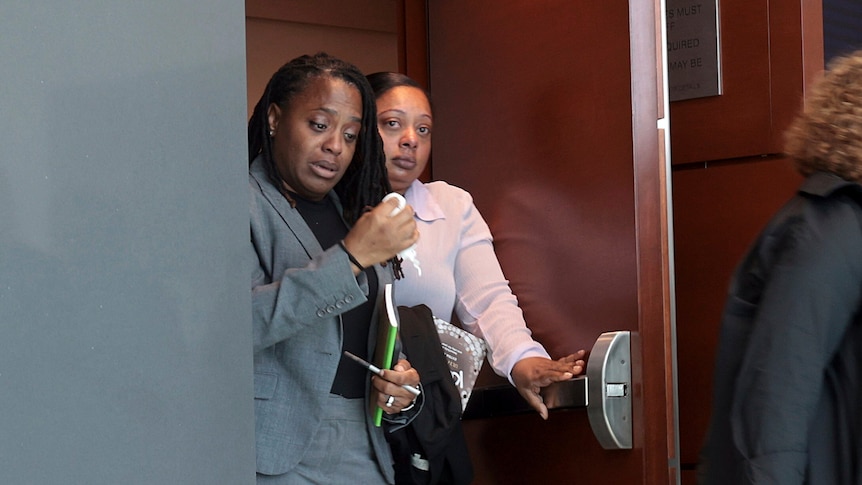 A woman is visibly upset, holding a tissue near her face as she exits a courtroom alongside parents of the Parkland shooting.