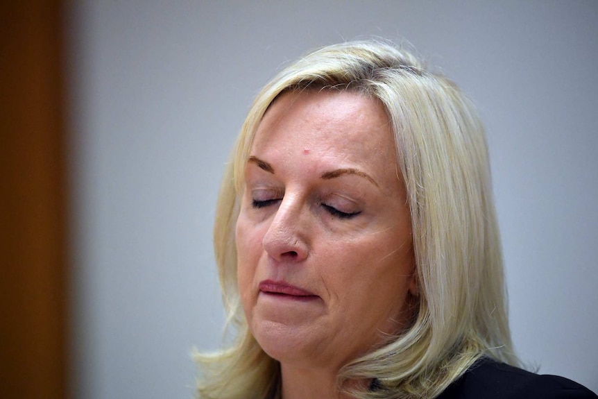 A head shot of a woman with blond hair who has her eyes closed.