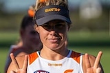Jacinda Barclay smiles and gives two peace signs while wearing Giants training gear