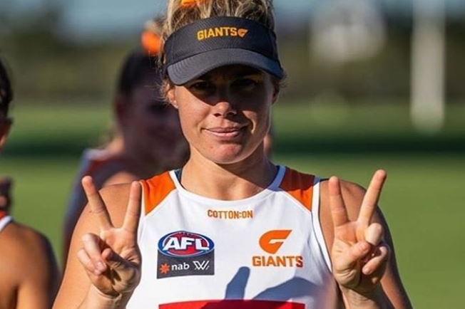 Jacinda Barclay smiles and gives two peace signs while wearing Giants training gear