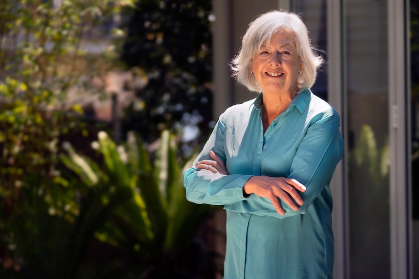 A lady with a teal shirt looking at camera smiling