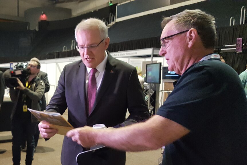 A man hands Prime Minister Scott Morrison a paper report
