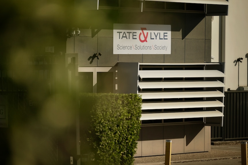 A photo showing a sign that reads Tate & Lyle on the front of a grey and white building.