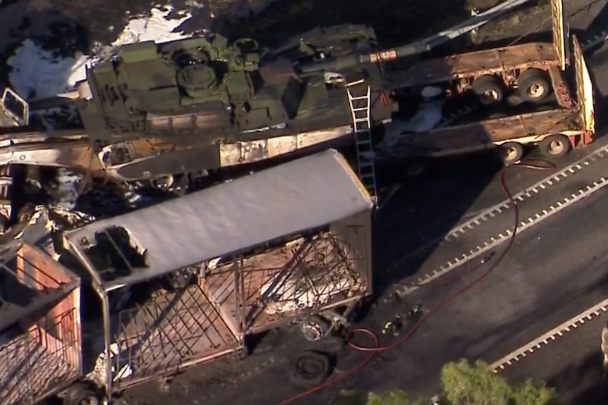 Aerial view of a tank on a semi-trailer next to a burnt shell of a B-Double truck