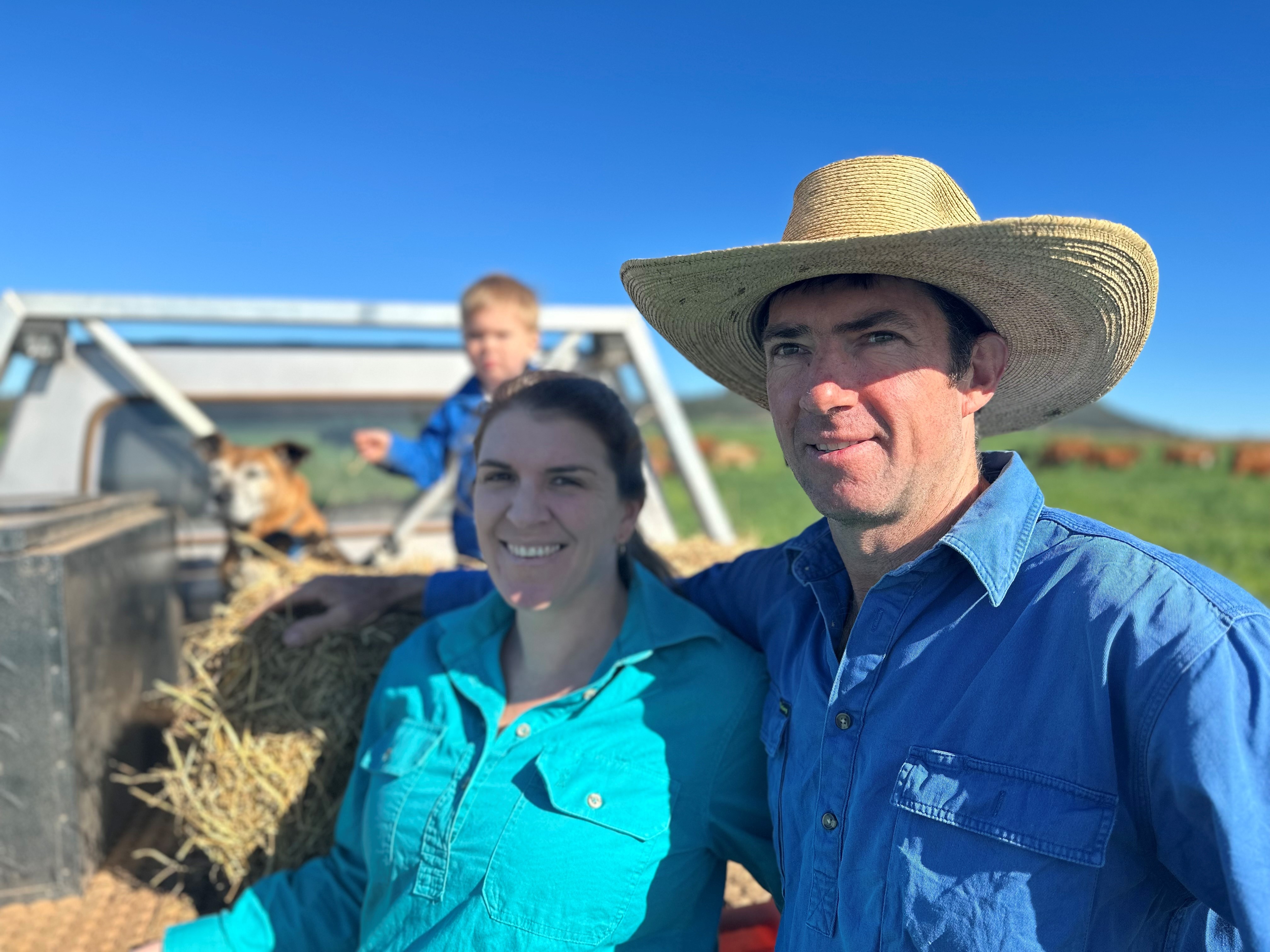 A man in a hat stands beside a woman in a green shirt.