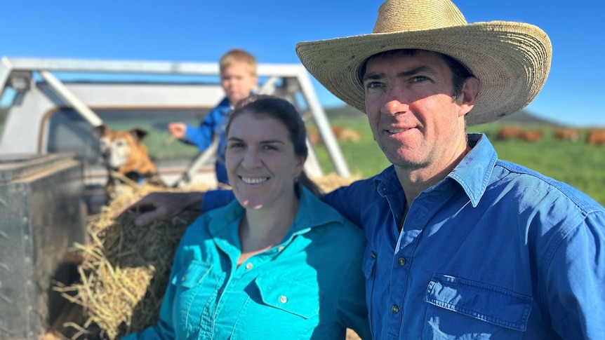 A man in a hat stands beside a woman in a green shirt.