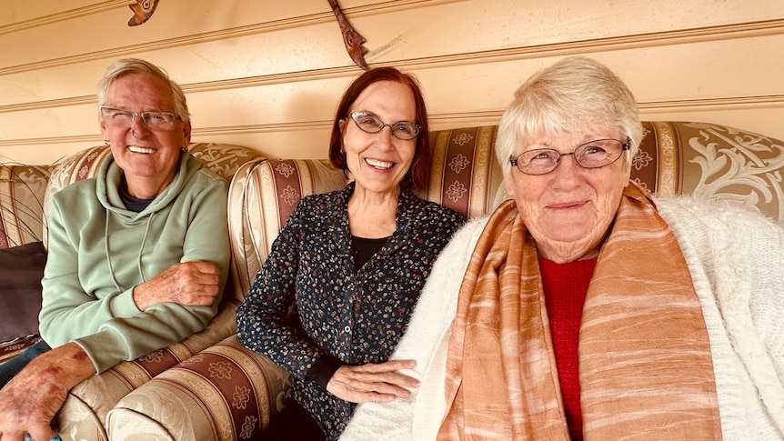 Older man and two older women smile at camera