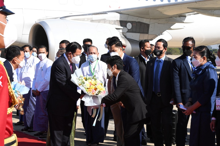 Cambodian Prime Minister Hun Sen receives floral bouquet on tarmac. 