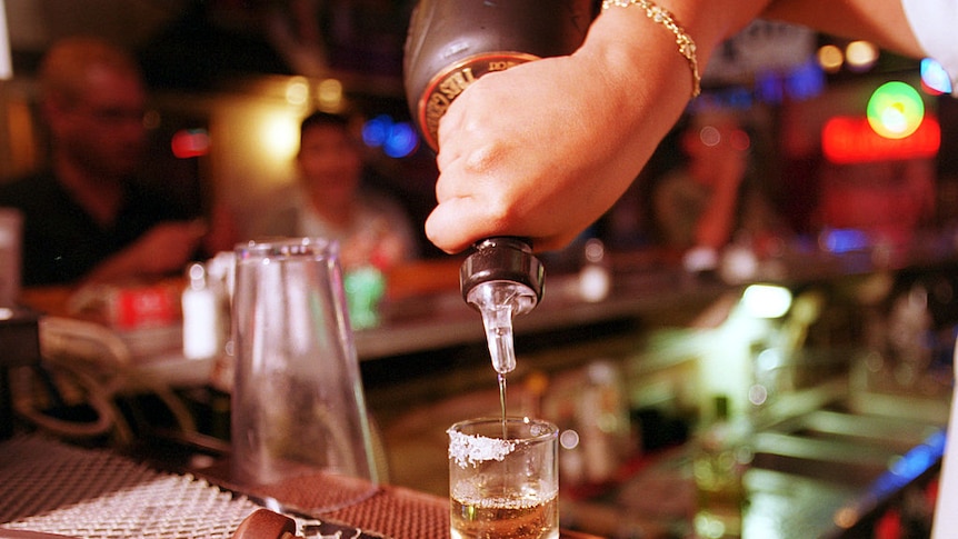 Shot glass being filled with alcohol