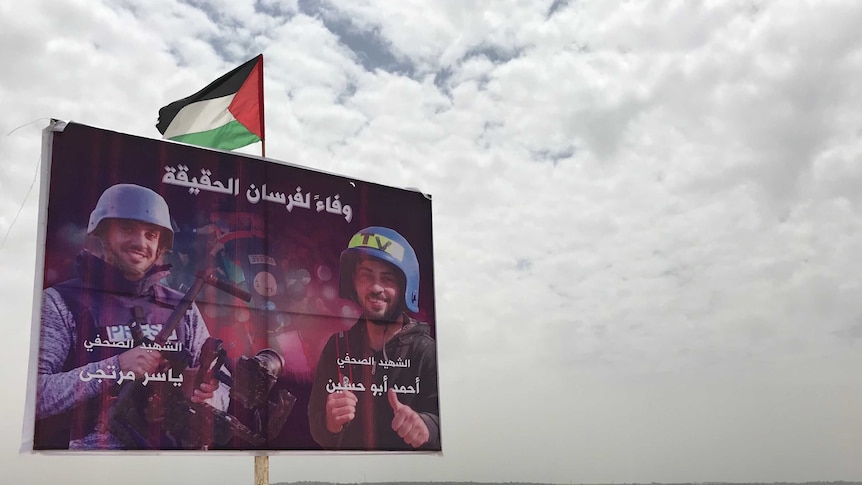 A poster of Palestinian journalists killed stands along the Israeli border