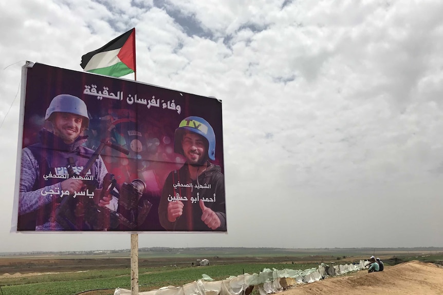 A poster of Palestinian journalists killed stands along the Israeli border