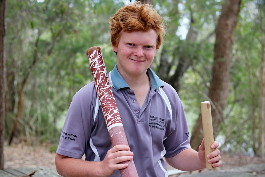 Michael James holds a didgeridoo and clapping stick at his home in Jervis Bay.