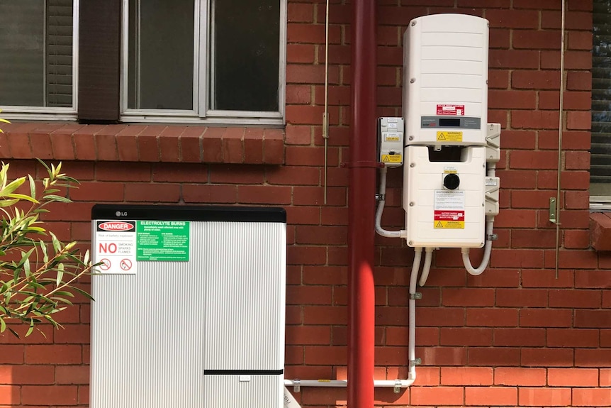 A solar battery unit on the side of a brick house.