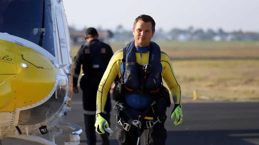 A man wearing rescue gear walks away from a helicopter