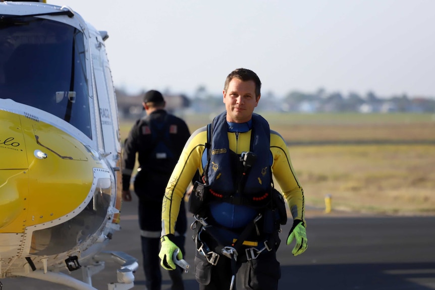 A man wearing rescue gear walks away from a helicopter