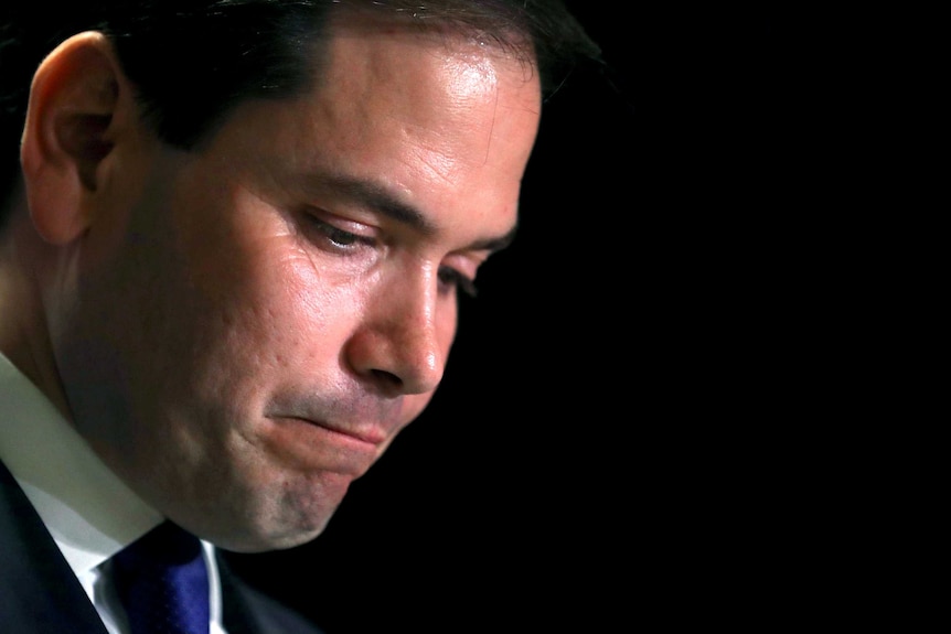 Marco Rubio hangs his head and looks dejected.