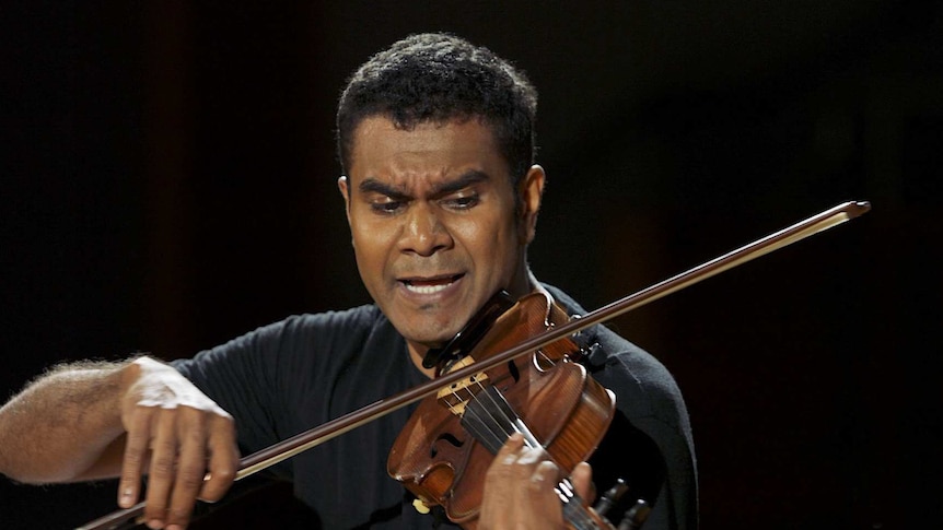 Violinist Eric Avery performing violin against a black backdrop.