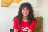 Hospitality worker Yasmine Sharaf sitting down wearing a red "Hospo Voice" shirt.