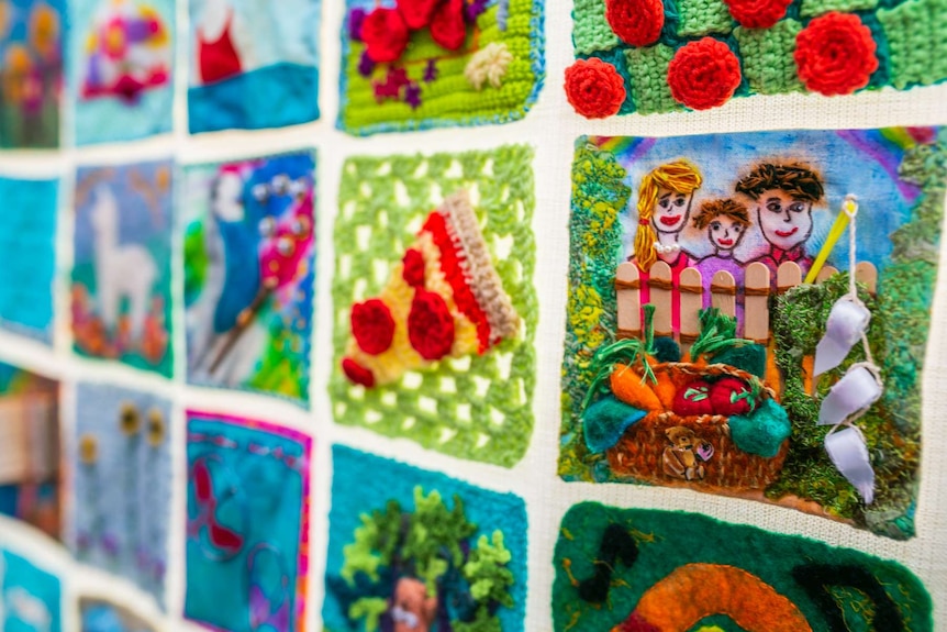 Two ladies looking closely at a quilt.