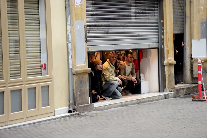 People take shelter inside a shop after an explosion in Istanbul