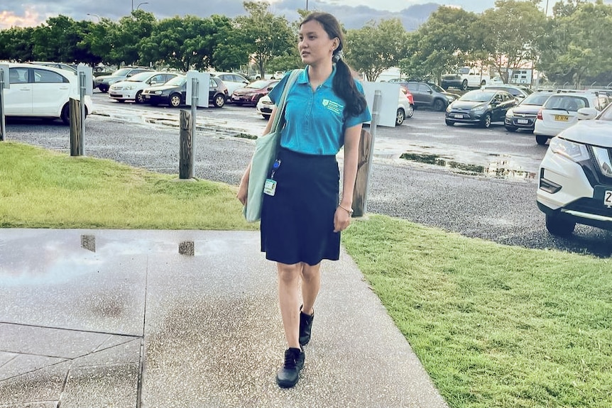 Alina poses in her student nurse uniform in front of a carpark.