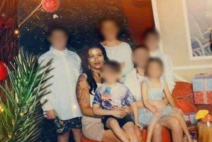 Woman and six children pose in formal photo with Santa seated to their left