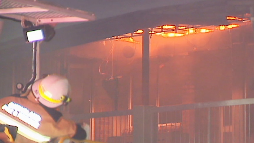 A firefighter battles fire on the second storey of a school building