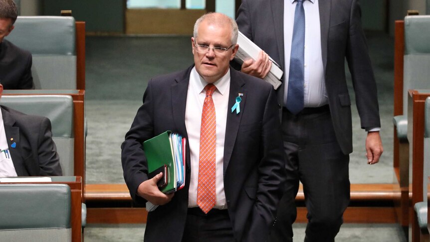 Mr Morrison has a bundle of folders under his arm, and is walking down the central aisle of the House of Representatives.