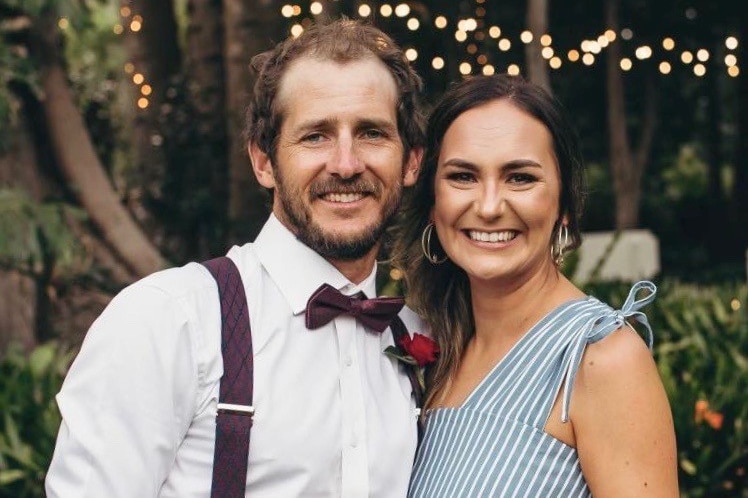 A man and woman smile at a wedding.